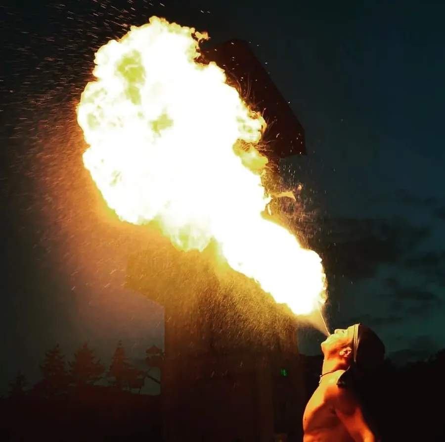 Feuerspucker Nuno blÀst einen riesigen Feuerball in der AbenddÀmmerung
