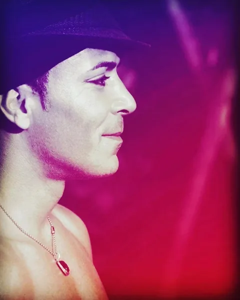 Portrait of fire breather and mentalist Nuno with hat in purple-red stage light