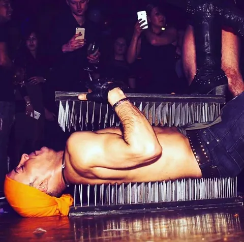 Fakir act in the club: Nuno lying between two beds of nails while a spectator stands on top