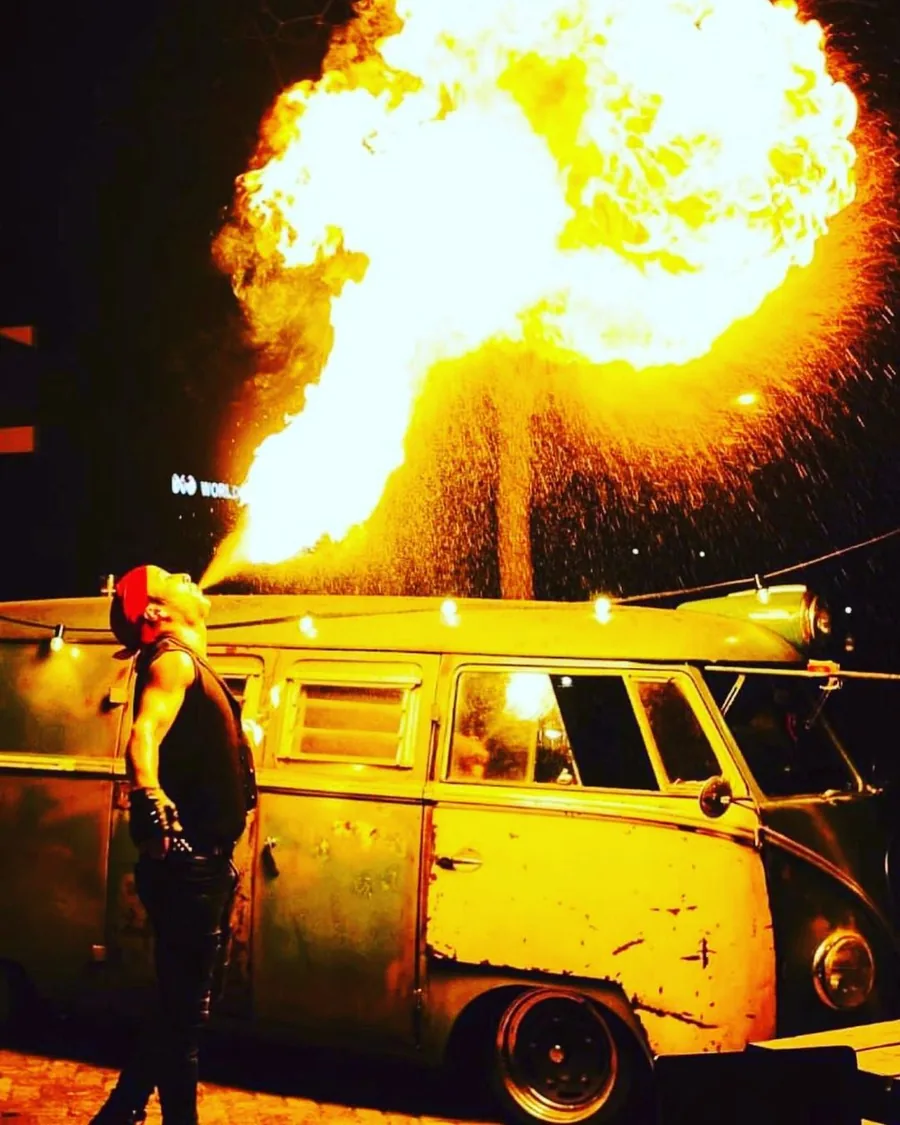 Vuurspuwer bij een vintage bus tijdens een themafeest in de avond