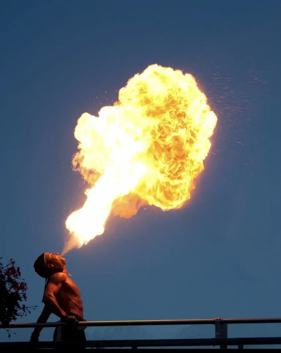 Feuerspucker bläst einen großen Feuerball gegen den Abendhimmel